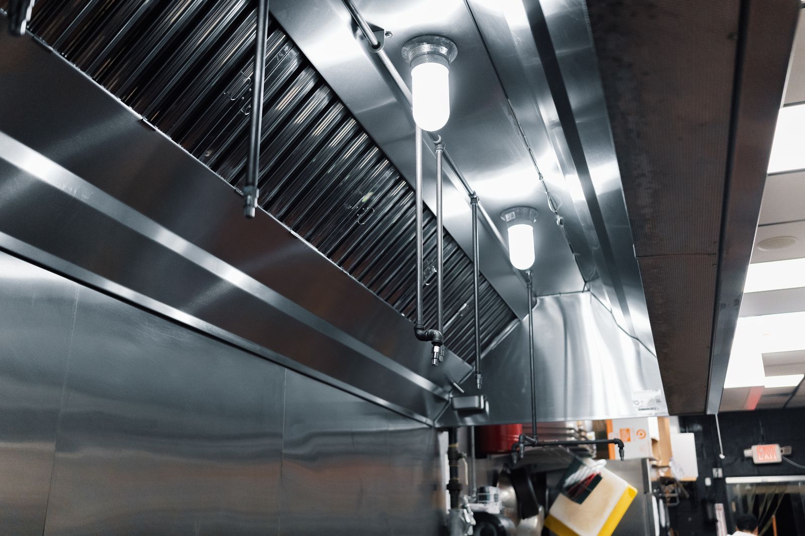 Gleaming stainless steel commercial kitchen hood with clean baffle filters and fire suppression nozzles after TruShine compliance cleaning