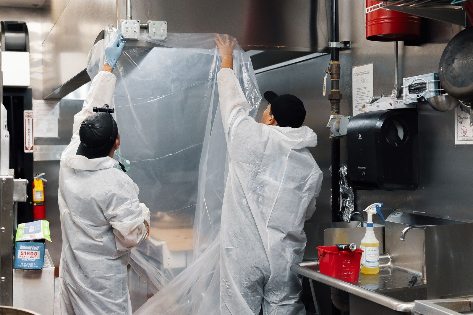 TruShine crew installing protective plastic sheeting on commercial kitchen hood before cleaning in Atlanta restaurant